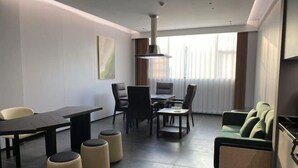 Una moderna camera d'albergo con angolo ristoro, divano e una grande finestra con tende.