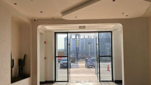 Ingresso di un hotel con porta in vetro, pavimento piastrellato e vista sulla strada.