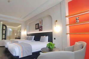 Habitació d'hotel amb un llit gran, zona de seients i una paret vermella decorativa.