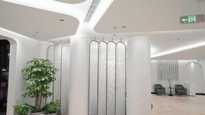 Una hall moderna con una colonna centrale, piante in vaso e un'area salotto.