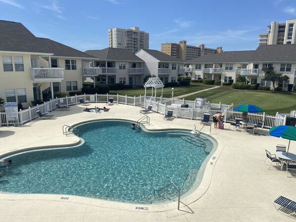 Relax by the oval-shaped pool surrounded by lounge chairs and umbrellas.