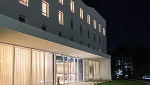 A modern building with a glass facade, a paved entrance, and a well-maintained lawn. - Flag Hotel Caldas da Rainha (Caldas da Rainha)