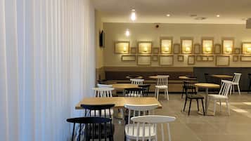 Un interior de restaurante moderno con mesas y sillas de madera, iluminación empotrada y una pared con diseño.