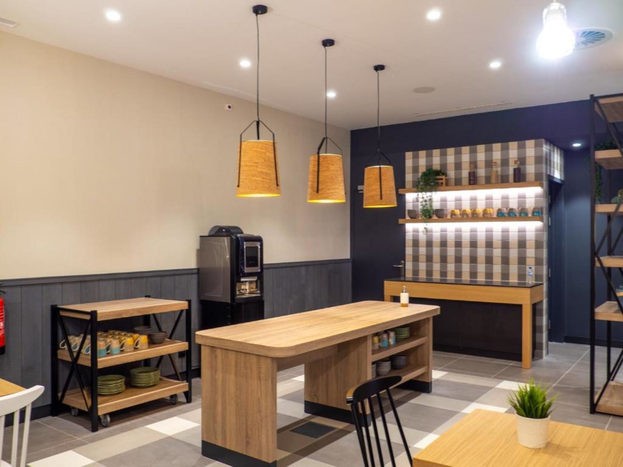 A modern cafe with a wooden counter, black chairs, and a coffee machine.