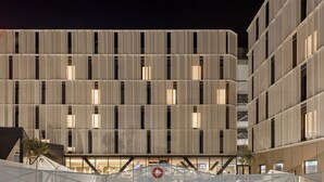 A modern building with a pool area, including a swimming pool and a safety sign. - Hampton by Hilton Alcobendas (Alcobendas)