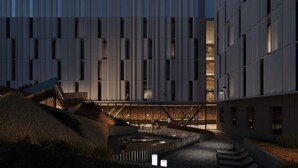 A modern building with a grid-like facade, a central courtyard with a water feature, and a staircase leading to an upper level. - Hampton by Hilton Alcobendas (Alcobendas)