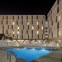 Un edificio moderno con zona de piscina, que incluye una alberca y un letrero de seguridad.