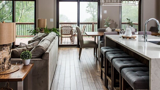 Une cuisine spacieuse avec de grandes fenêtres, un coin repas avec une table et des chaises en bois, et un bar avec des tabourets.
