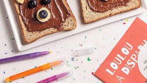 Two slices of toast with chocolate spread and blueberries, colorful markers, a notebook titled 'LOULOU A DISPARU', and a plate with an orange slice. - Ibis Styles Puteaux Paris La Defense (Puteaux)