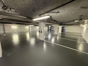 Eine Tiefgarage mit mehreren Parkplätzen, Betonpfeilern und Beleuchtung.