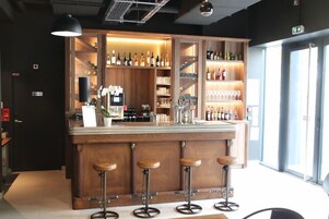 Un espacio de bar con taburetes de madera, estantes llenos de botellas y vasos.