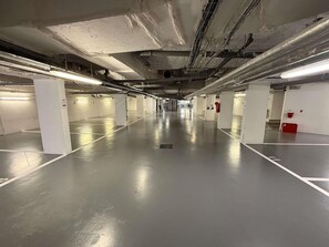 A parking garage with multiple parking spaces, white pillars, and overhead lighting. - Ibis Styles Puteaux Paris La Defense (Puteaux)