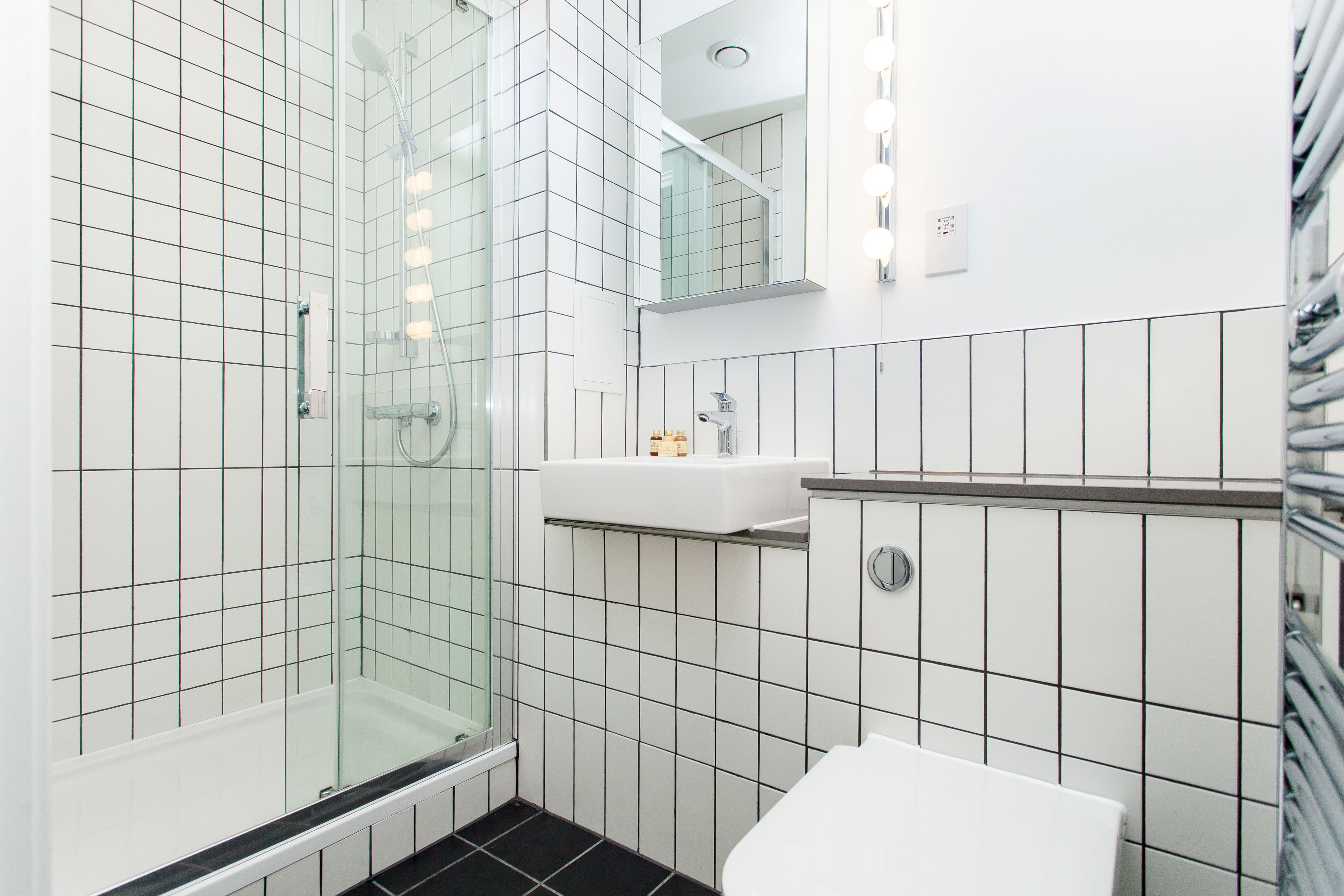 Une salle de bain moderne avec une douche à parois de verre, un lavabo blanc et des toilettes.