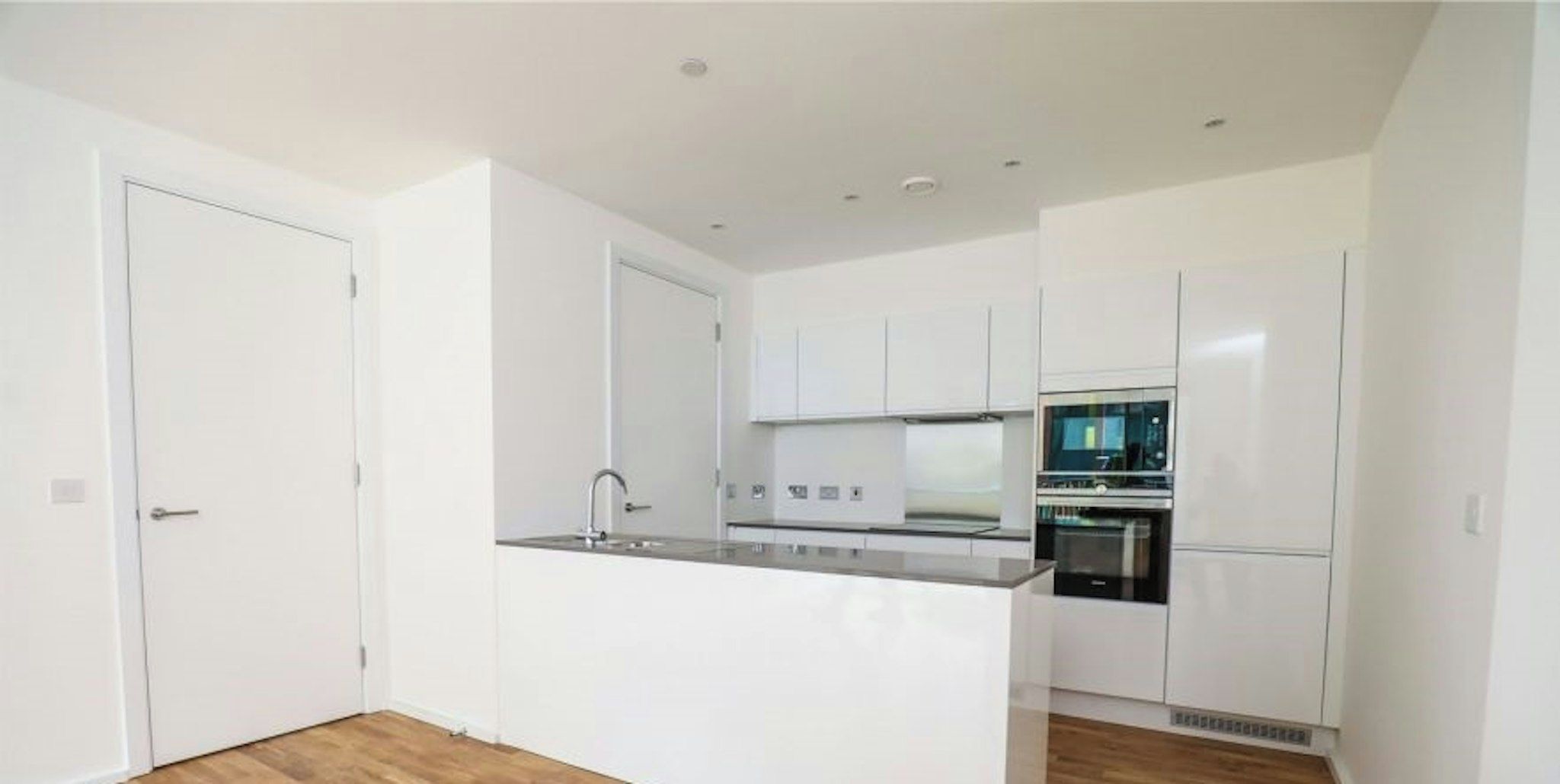 A modern kitchen with white cabinetry, a built-in oven, and a countertop.