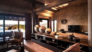 Una sala de estar moderna con un ventanal que ofrece vistas panorámicas, un espacio de descanso cómodo y un televisor de pantalla plana.