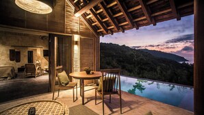 Terraza de madera con vista a un paisaje montañoso y una piscina.