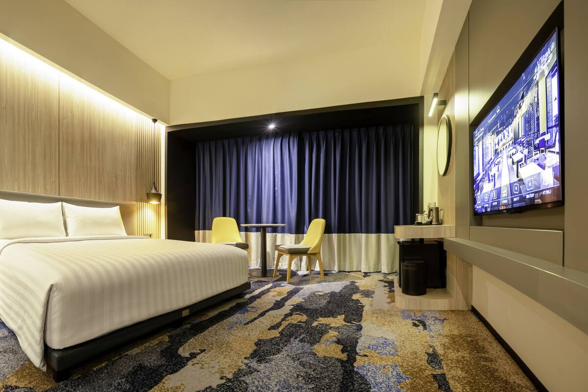 Une chambre d’hôtel avec un grand lit, un bureau, une chaise, une télévision et un mini-bar.