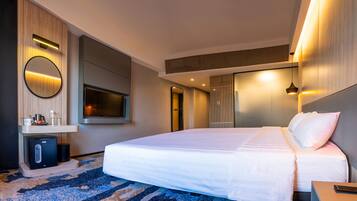 A modern hotel room with a large bed, a flat-screen TV, a bedside table, a mirror, and a built-in heater.
