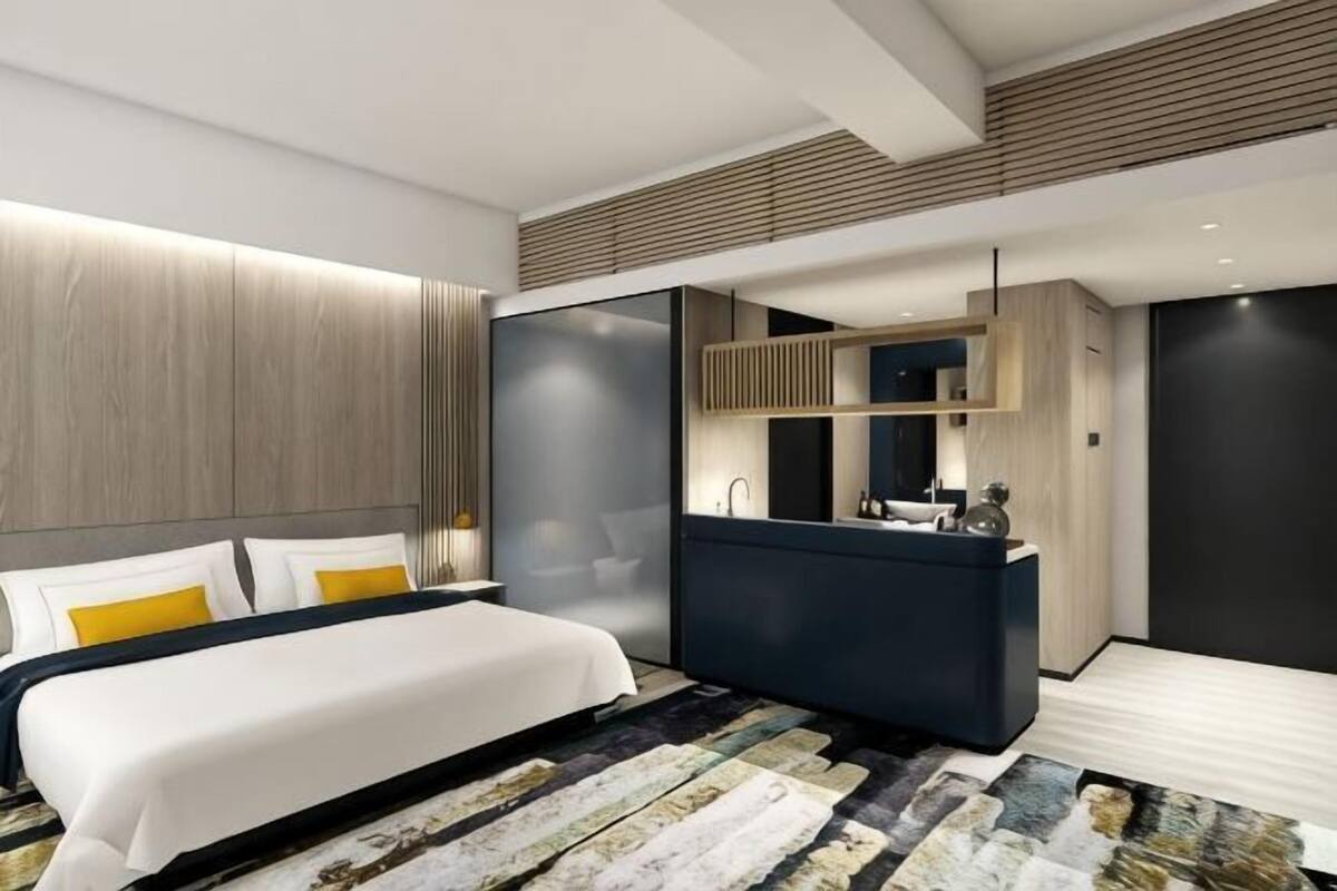 Une chambre d’hôtel moderne avec un grand lit, un bureau intégré et un miroir.