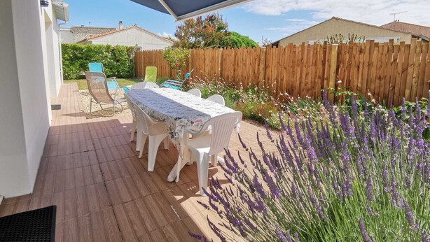 Eine Terrasse im Freien mit Tisch und Stühlen, einem Holzzaun und Lavendelpflanzen.