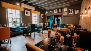 A restaurant with wooden floors, tables set with candles and glassware, and framed pictures on the walls. - OYO The Leven (Middlesbrough)
