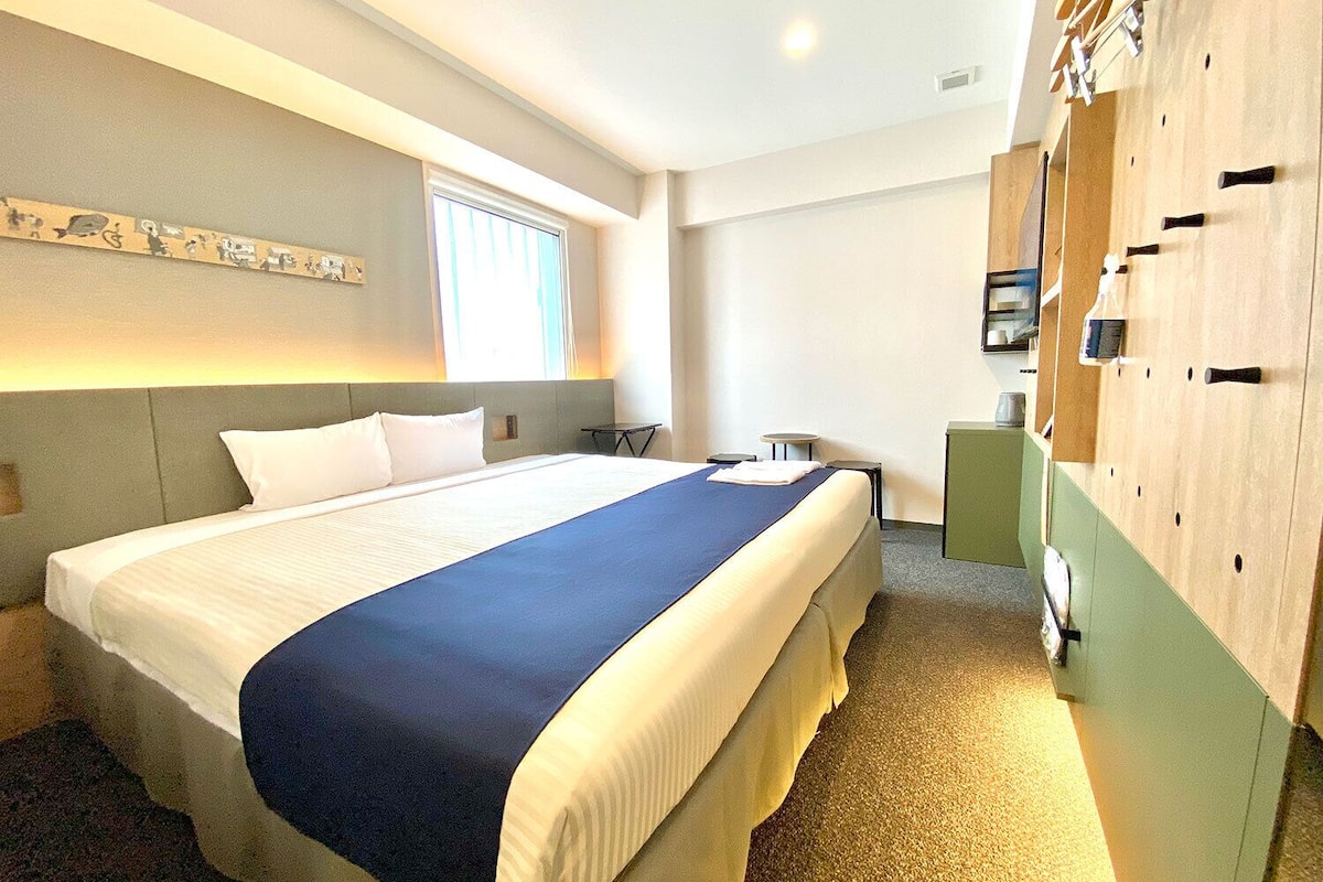 Une chambre d’hôtel avec un grand lit, un bureau, une armoire et une fenêtre.