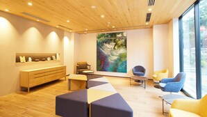A modern interior with a wooden ceiling, a large abstract painting, and a seating area with various chairs and a sofa. - Hotel Monday Premium Ueno Okachimachi (Tokyo)
