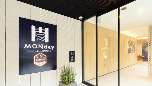 A hotel entrance with a large sign reading "MONday hotel OKACHIMACHI PREMIUM" and a reception area visible through glass doors. - Hotel Monday Premium Ueno Okachimachi (Tokyo)