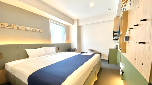 A hotel room with a large bed, a bedside table, a chair, a wardrobe, and a window. - Hotel Monday Premium Ueno Okachimachi (Tokyo)