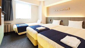 Habitación de hotel con dos camas, una mesita redonda, una ventana con cortinas y una obra de arte colgada en la pared.