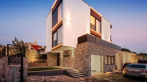 A modern two-story house with a stone facade, a carport, and a well-lit entrance. - Villa Emotha-Five Bedroom villa with Pool (Korcula)