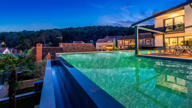 A swimming pool with a view of a modern house and surrounding buildings. - Villa Emotha-Five Bedroom villa with Pool (Korcula)