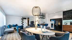 A modern living room with a round dining table, grey sofas, and a kitchen area with a black refrigerator and marble backsplash. - Villa Emotha-Five Bedroom villa with Pool (Korcula)