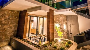 A modern multi-story building with a glass balcony, stone facade, and a landscaped outdoor seating area. - Villa Emotha-Five Bedroom villa with Pool (Korcula)