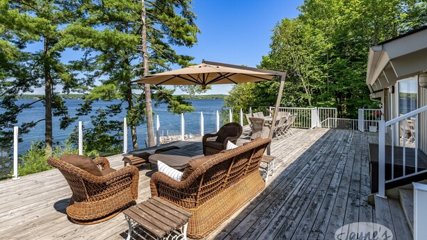 A wooden deck with wicker furniture, a pergola, and a view of a lake. - Island Property on Lake Muskoka! 4brdm, 3 bath! Best Internet! SUP, Kayak (Bracebridge)