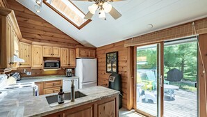 A kitchen with wooden cabinets, a microwave, a refrigerator, and a large window overlooking a deck. - Island Property on Lake Muskoka! 4brdm, 3 bath! Best Internet! SUP, Kayak (Bracebridge)