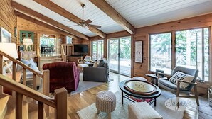 A spacious cabin interior with a wooden interior, a dining area, and large windows offering views of the outdoors. - Island Property on Lake Muskoka! 4brdm, 3 bath! Best Internet! SUP, Kayak (Bracebridge)