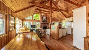 A rustic cabin interior with a wooden dining table, a cozy seating area, a fireplace, and a kitchen with a refrigerator. - 8 bedroom 4 bath Island getaway on Lake Rosseau! (Muskoka Lakes)