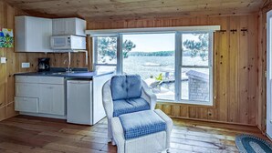 A cabin with a kitchen, a dining area with a chair, and a large window overlooking a lake. - 8 bedroom 4 bath Island getaway on Lake Rosseau! (Muskoka Lakes)