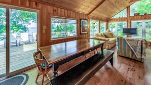 A wooden cabin interior with a large dining table, a sofa, and a TV. - 8 bedroom 4 bath Island getaway on Lake Rosseau! (Muskoka Lakes)