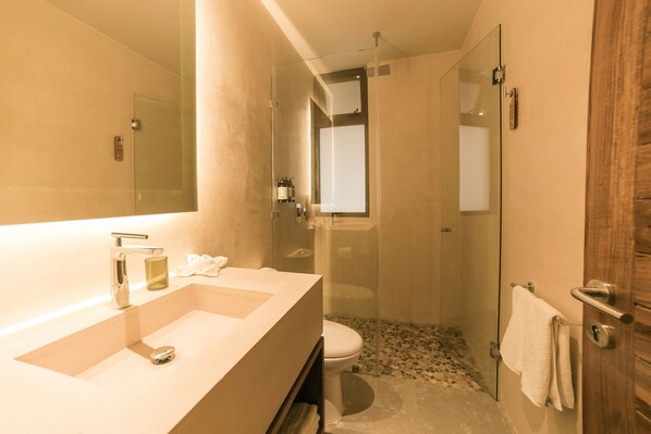 A modern bathroom with a large sink, mirror, and glass shower enclosure. - Zereno Tulum Beach Club Access (Tulum)