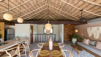 Una cocina amplia con una isla central, sillas de madera y una lámpara colgante.