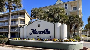 A sign for Maravilla with a number 2606, surrounded by a flower bed and palm trees. - 🏖️ Maravilla ~ private beach ~ includes beach setup of 4 chairs, 2 umbrellas 🏖️ (Miramar Beach)