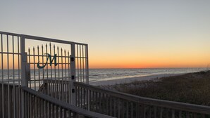A wooden boardwalk leading to a beach with a gate featuring a large 'M' emblem. - 🏖️ Maravilla ~ private beach ~ includes beach setup of 4 chairs, 2 umbrellas 🏖️ (Miramar Beach)