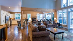 A spacious living area with a large sofa set, a dining table, and a kitchen in the background. - 4 bedroom, 4 bath, Quiet Butterfly Lake! Port Carling! Cozy & Spacious! (Port Carling)