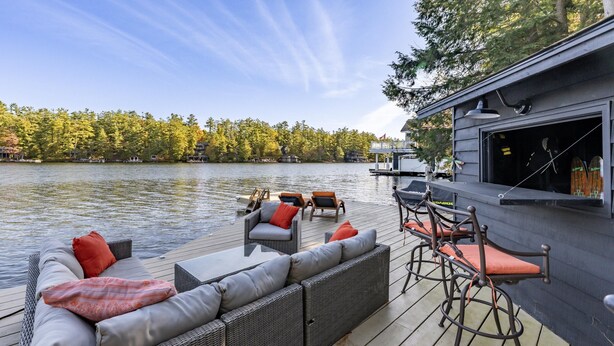 A waterfront deck with a sofa, chairs, and a bar area.