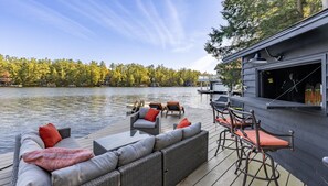 A waterfront deck with a sofa, chairs, and a bar area. - 3+ bdrm, 3 bath, Bunkie, Luxury, Lake Muskoka, Miles of boating on the Big 3! (Gravenhurst)