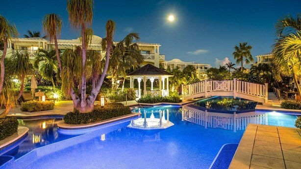 A swimming pool with a bridge, palm trees, and a gazebo. - Spectacular Beachfront Condo, Ocean Views of Grace Bay, Suite #123 (Providenciales)