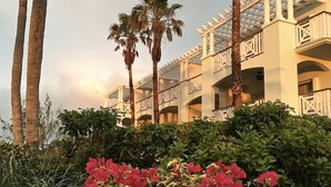 A hotel with multiple balconies, palm trees, and lush greenery. - Spectacular Beachfront Condo, Ocean Views of Grace Bay, Suite #123 (Providenciales)