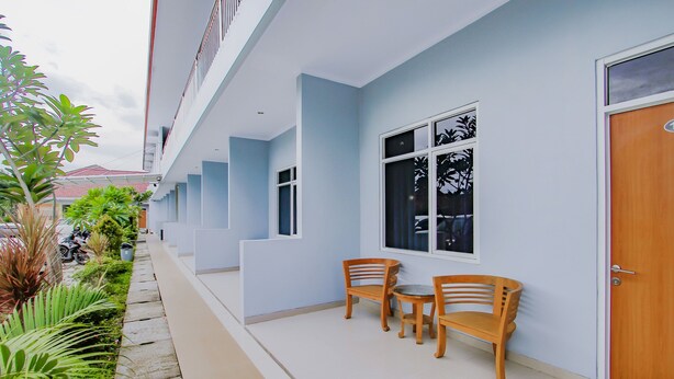 A hotel corridor with a row of windows, a wooden bench, and a door. - OYO 3277 Inayah Pkpri Hotel Syariah (Serang)